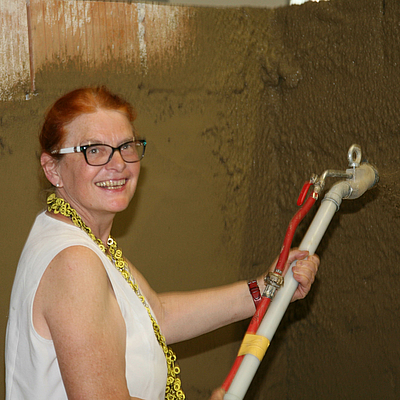 Lachende Frau spritzt Lehm auf eine Wand